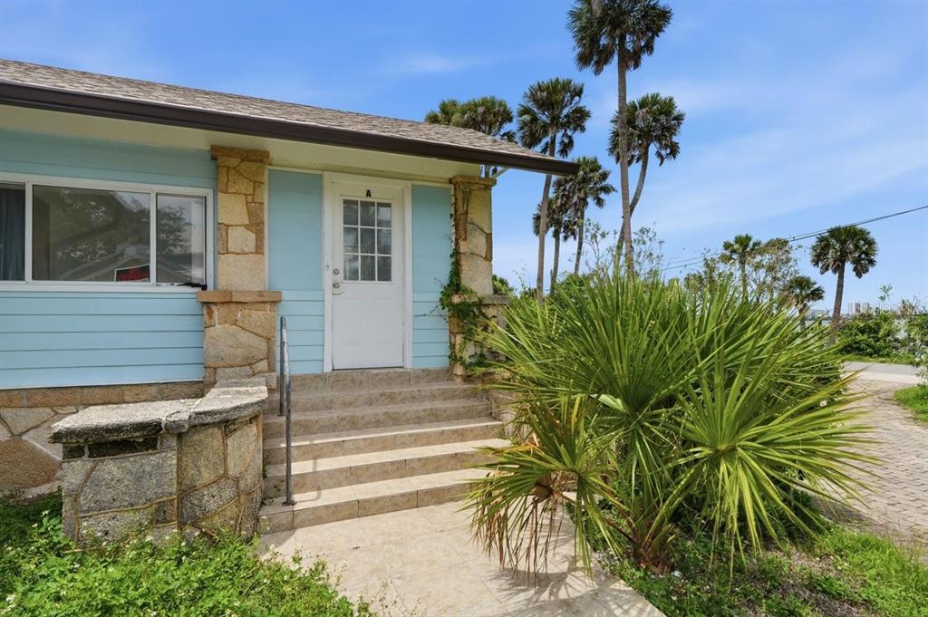 The exterior of a light blue house features a stone-accented porch, stairs, and palm trees — 5202 RIVERSIDE DRIVE, PORT ORANGE, FL