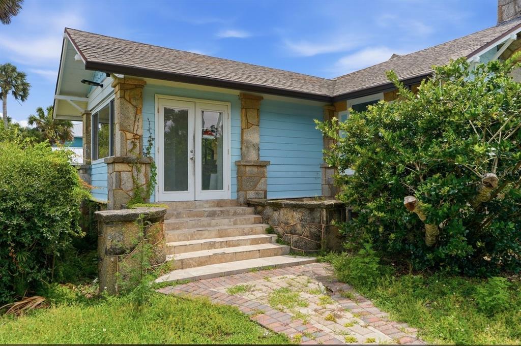 A light blue house exterior features stone pillars, a brick walkway, and a set of stairs — 5202 RIVERSIDE DRIVE, PORT ORANGE, FL