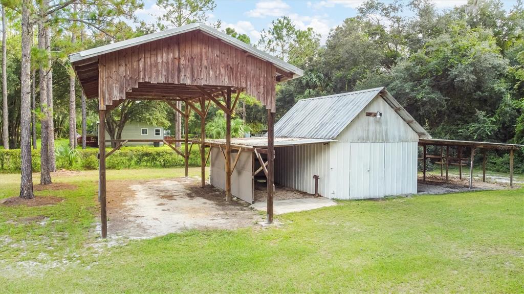 A yellow single-story house with a white metal roof sits behind a white picket fence — 17925 SE 49TH PLACE, HAWTHORNE, FL