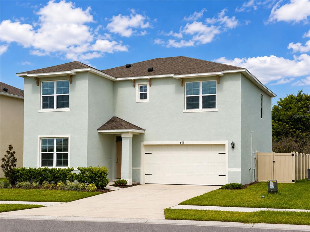 A two-story light green house with a two-car garage and a concrete driveway — 869 AMBLESIDE DRIVE, HAINES CITY, FL