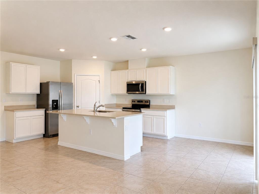 A kitchen with white cabinets, stainless steel appliances, a center island, and tile flooring — 869 AMBLESIDE DRIVE, HAINES CITY, FL