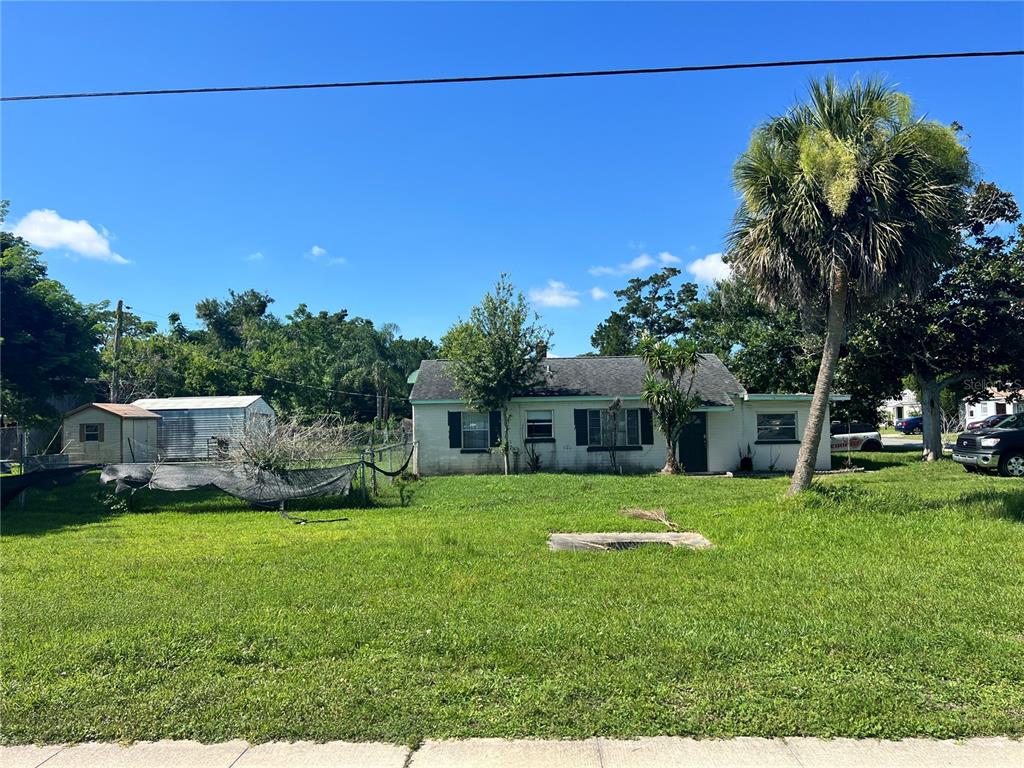 A single-story house with a large front yard, a palm tree, and a metal shed — 104 GRACE AVENUE, COCOA, FL