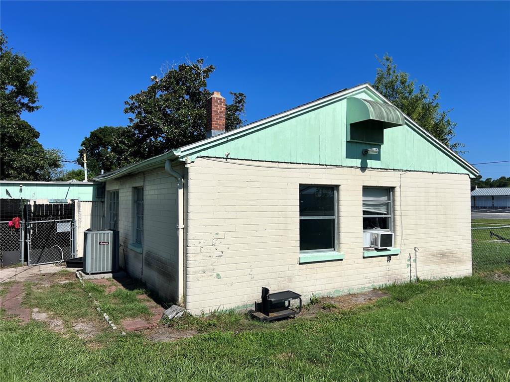 The exterior of a single-story building features painted brick walls and a green gable roof — 104 GRACE AVENUE, COCOA, FL