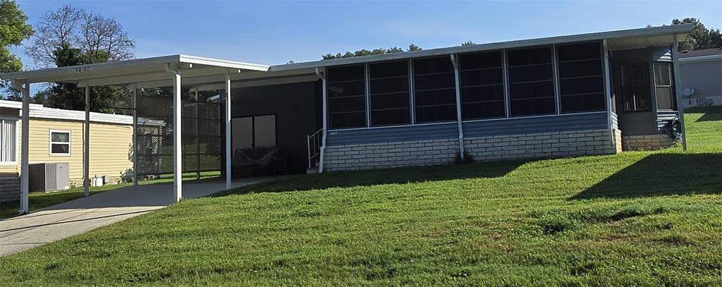 A manufactured home with a carport, a screened-in porch, and a brick-patterned lower exterior wall — 4007 COHEN DRIVE UNIT 742, ZELLWOOD, FL