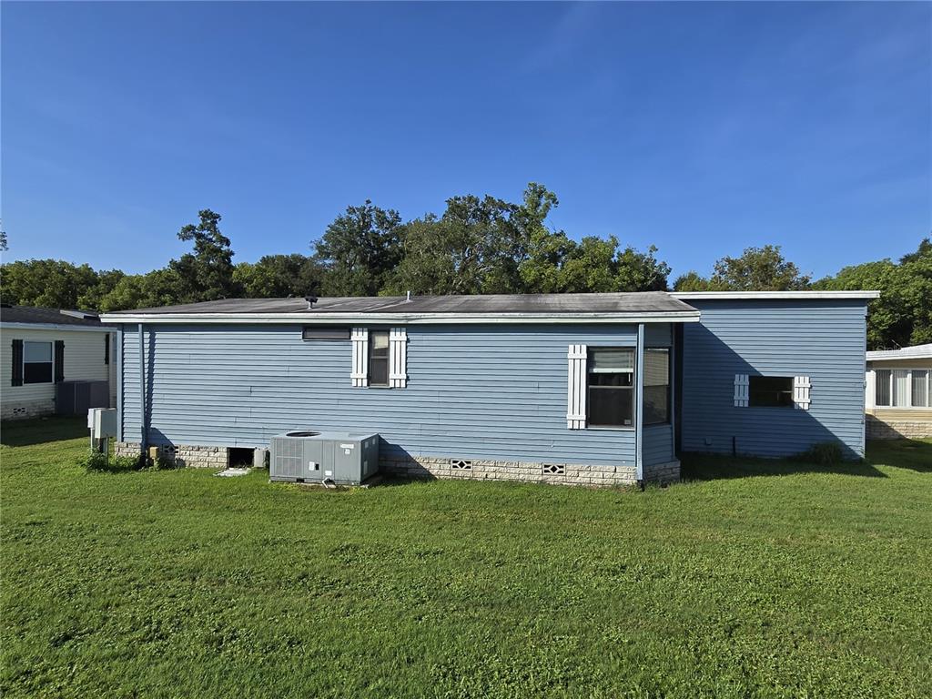 The exterior of a blue manufactured home features horizontal siding, white shutters, and a central air-conditioning unit — 4007 COHEN DRIVE UNIT 742, ZELLWOOD, FL