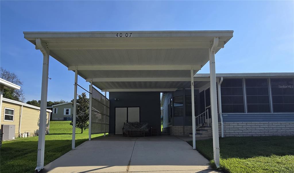 A concrete driveway leads to a covered carport attached to a mobile home — 4007 COHEN DRIVE UNIT 742, ZELLWOOD, FL