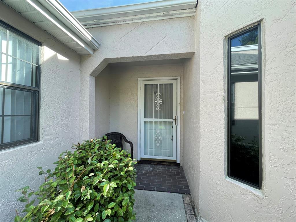A front entryway features a white storm door, a brick porch, and a large bush — 6793 E DOWNING STREET, INVERNESS, FL