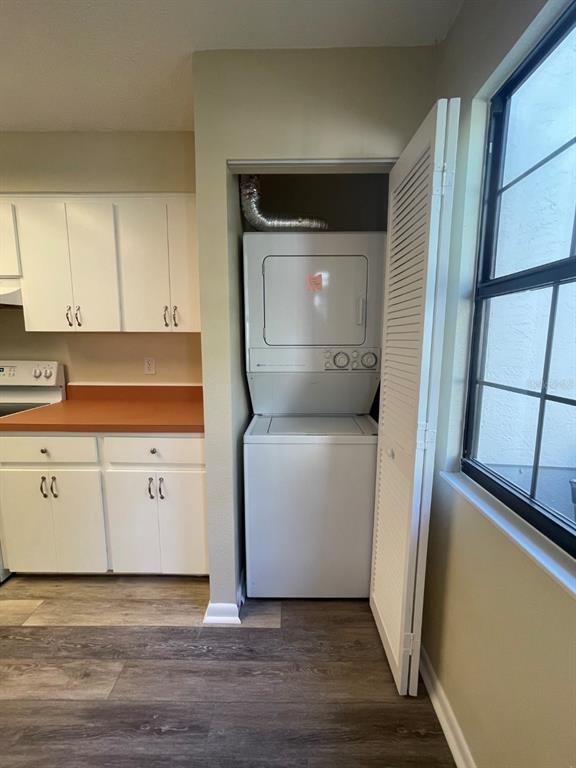 A kitchen features white cabinets, a reddish countertop, and a stacked washer-dryer unit in a closet — 6793 E DOWNING STREET, INVERNESS, FL