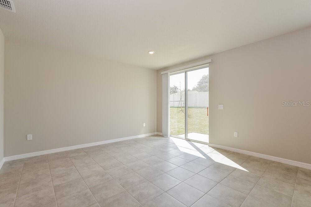 An empty room with light-colored tile flooring and a sliding glass door leading outside — 1026 OAK VALLEY DRIVE, AUBURNDALE, FL