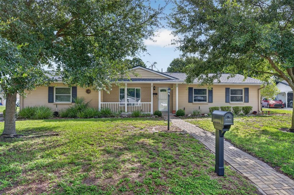 A single-story house with a brick and tan exterior, a front porch, and a paved walkway — 2641 CARVELL COURT, WINTER PARK, FL