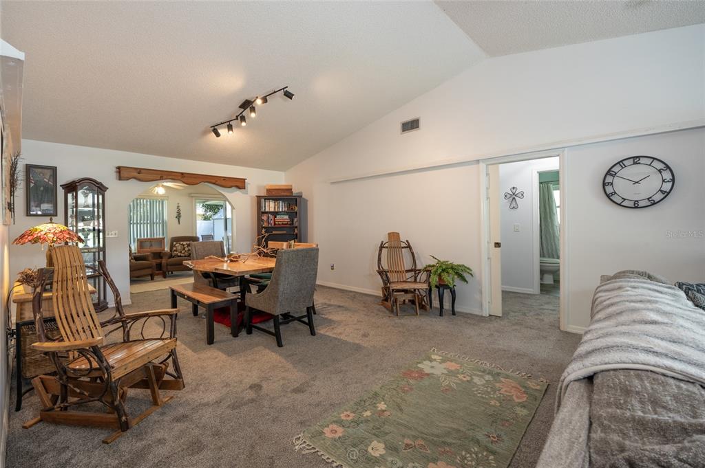 A living room with gray carpet, a wooden rocking chair, and a dining area beyond — 6 BOXWOOD LANE, PALM COAST, FL