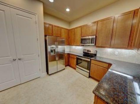 A kitchen with wood cabinets, stainless steel appliances, and dark granite countertops — 802 ALDENHAM LANE, ORMOND BEACH, FL
