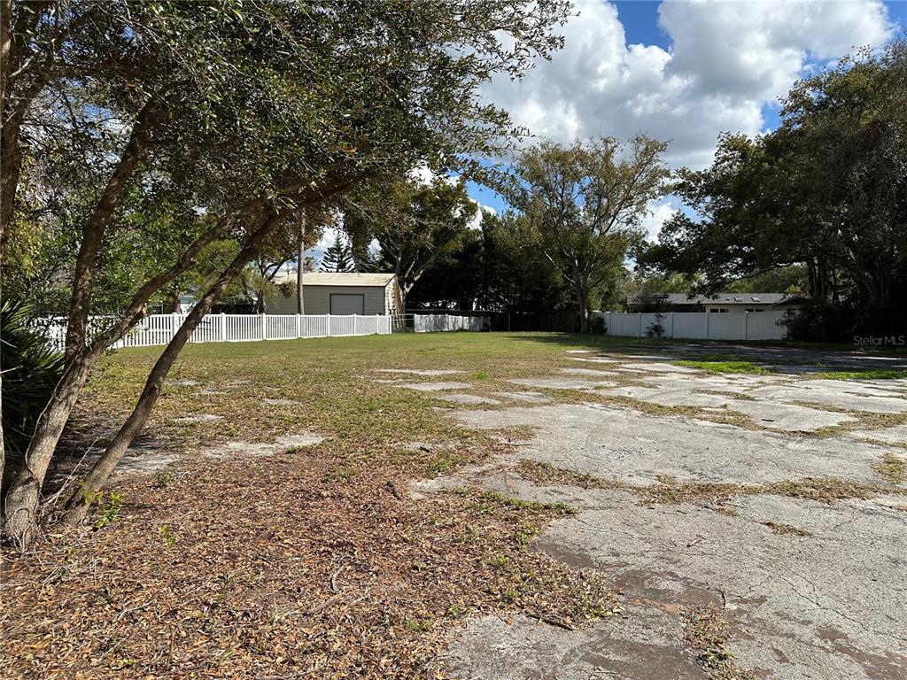 A large, partially paved vacant lot features a white fence and mature trees — SUNRISE DRIVE, LUTZ, FL