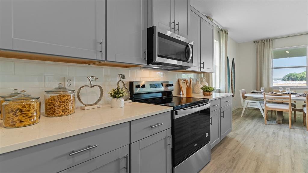 A kitchen features gray cabinets, stainless steel appliances, white countertops, and an adjacent dining area — 3033 KINGSMAN TRAIL, ORMOND BEACH, FL