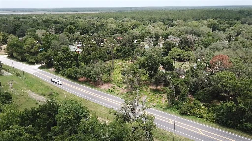 An aerial view shows a paved road running alongside a wooded lot with scattered trees — COUNTY ROAD 42, UMATILLA, FL