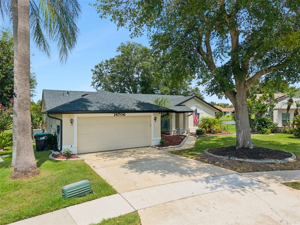 A single-story house with a beige stucco exterior, a two-car garage, and a front lawn — 14706 EAGLE VIEW COURT, ORLANDO, FL