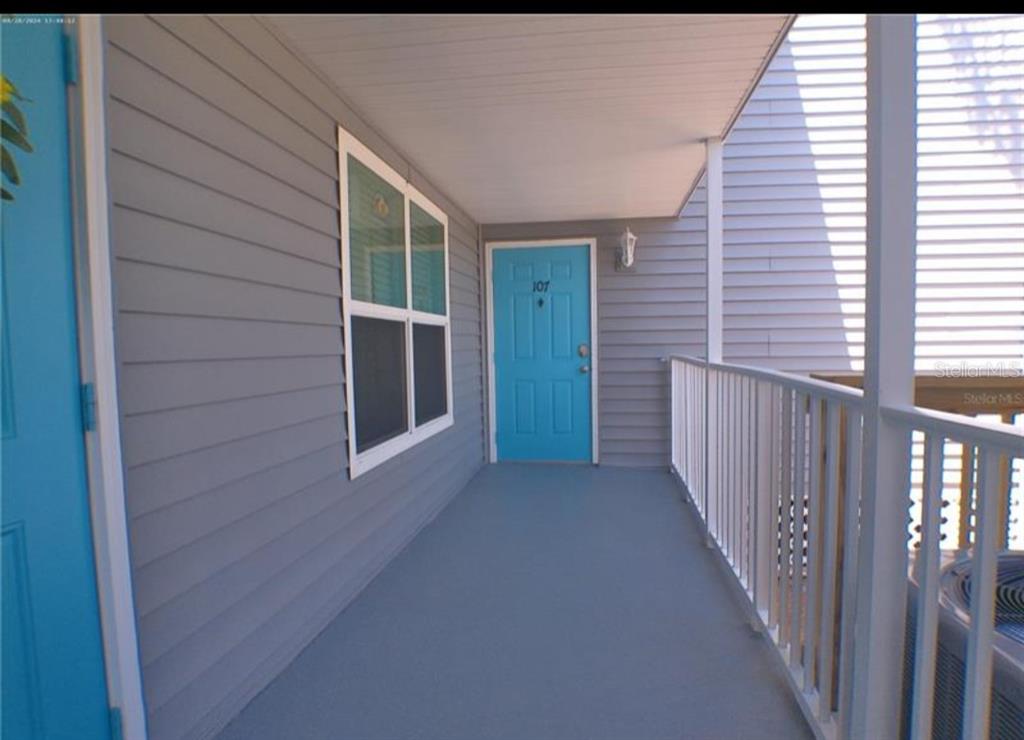 A swimming pool sits between apartment buildings and a body of water under a blue sky — 4410 WARREN AVENUE UNIT 107, PORT CHARLOTTE, FL