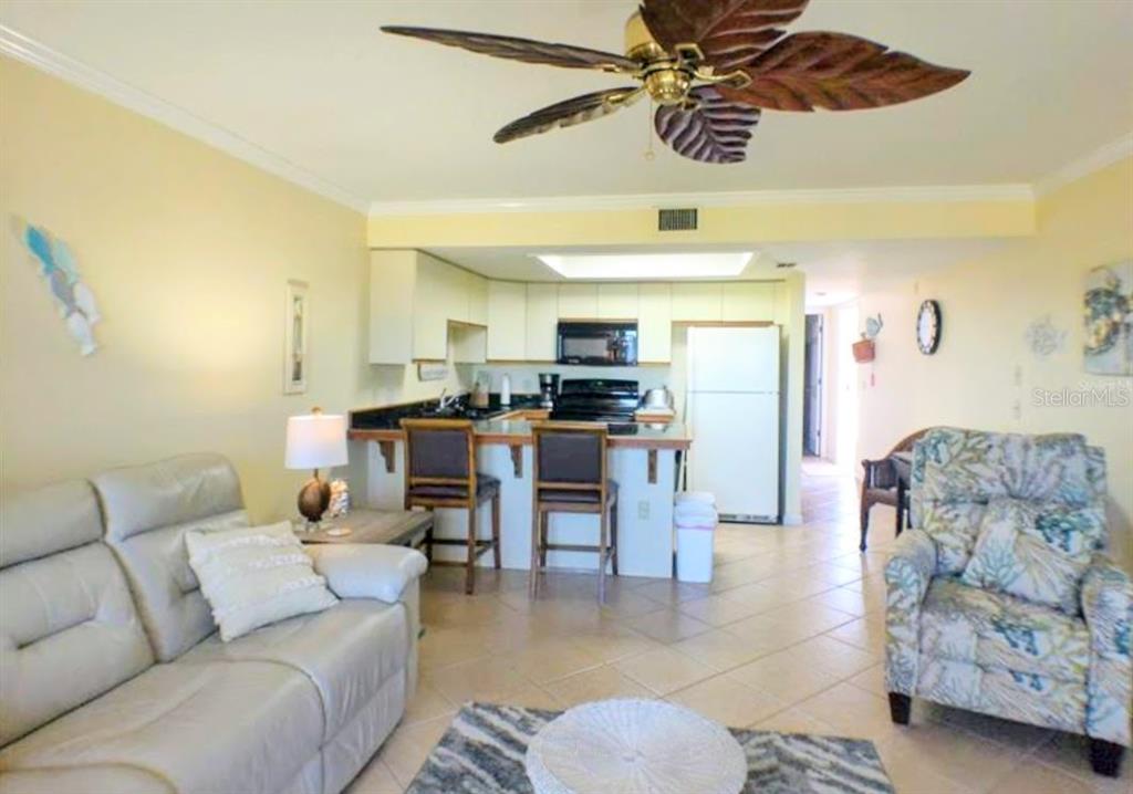 A swimming pool sits beside a two-story building with blue doors and a metal roof — 4410 WARREN AVENUE UNIT 107, PORT CHARLOTTE, FL