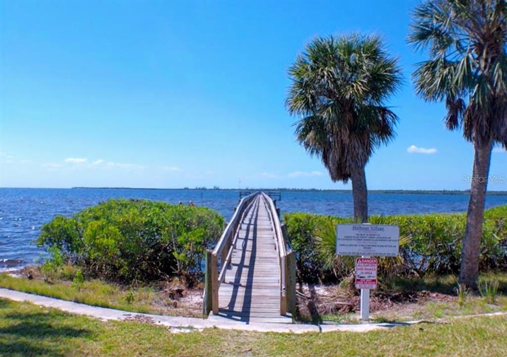 A rectangular swimming pool sits on a paved deck between two multi-story residential buildings — 4410 WARREN AVENUE UNIT 107, PORT CHARLOTTE, FL