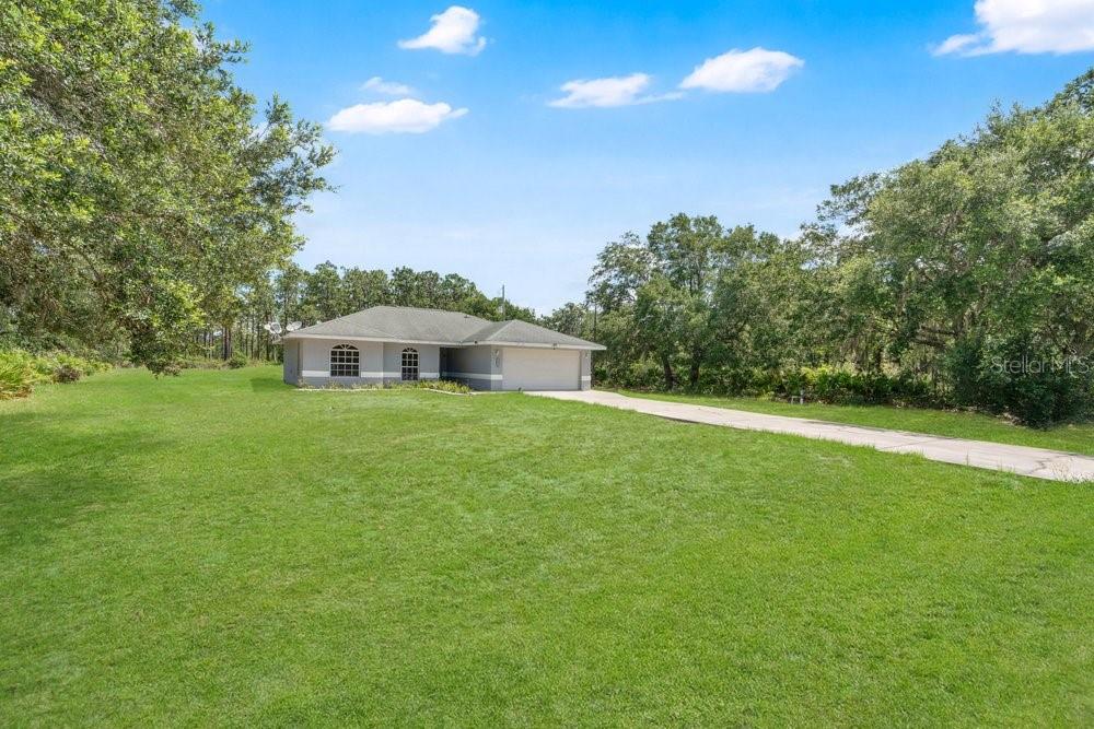 A bedroom features light gray walls, wood-look flooring, a single window, and white louvered closet doors — 3450 PARK AVENUE, INDIAN LAKE ESTATES, FL