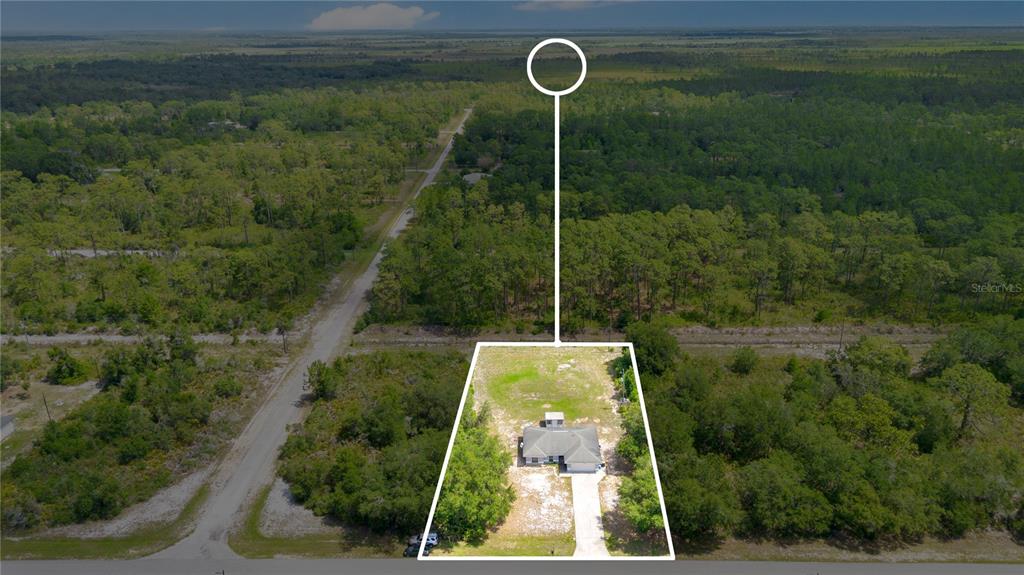 An empty room with gray wood-look flooring, white walls, and an arched window — 3450 PARK AVENUE, INDIAN LAKE ESTATES, FL