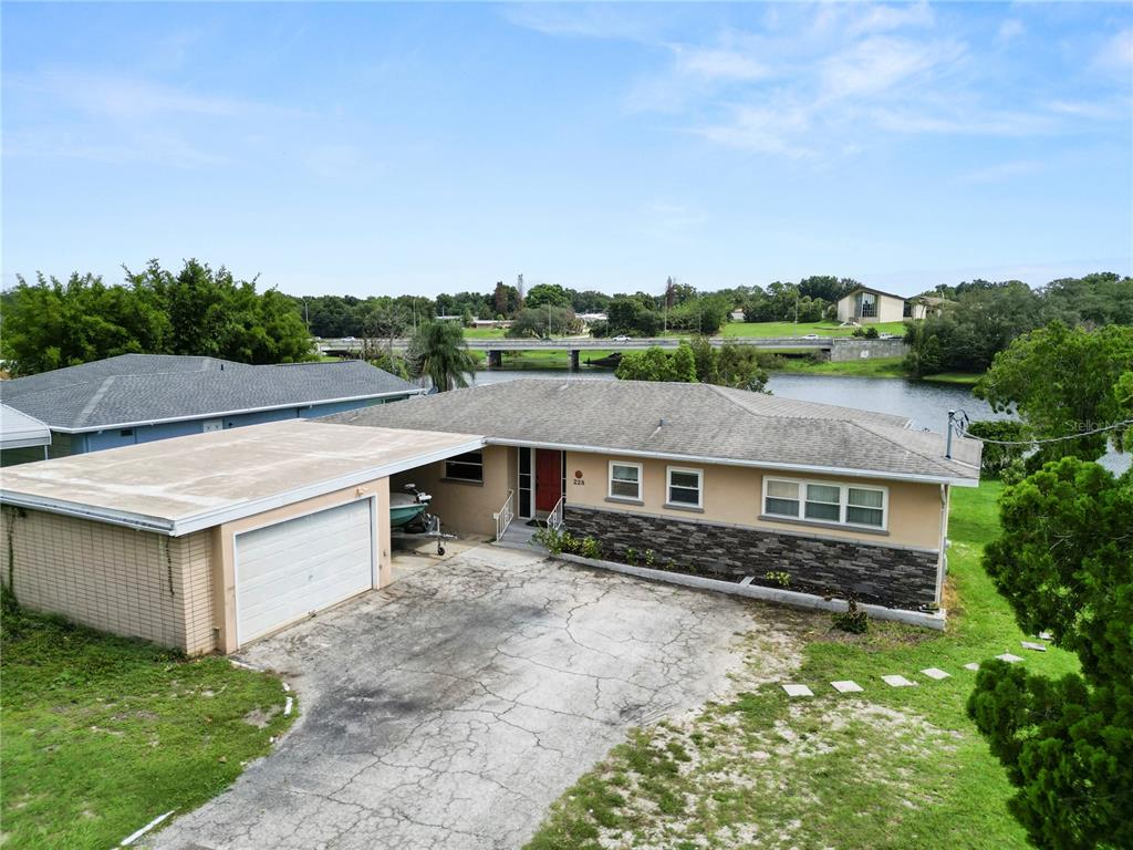 An exterior view of a single-story house with a carport, stone facade, and a driveway — 228 W LAKE INA DRIVE, WINTER HAVEN, FL