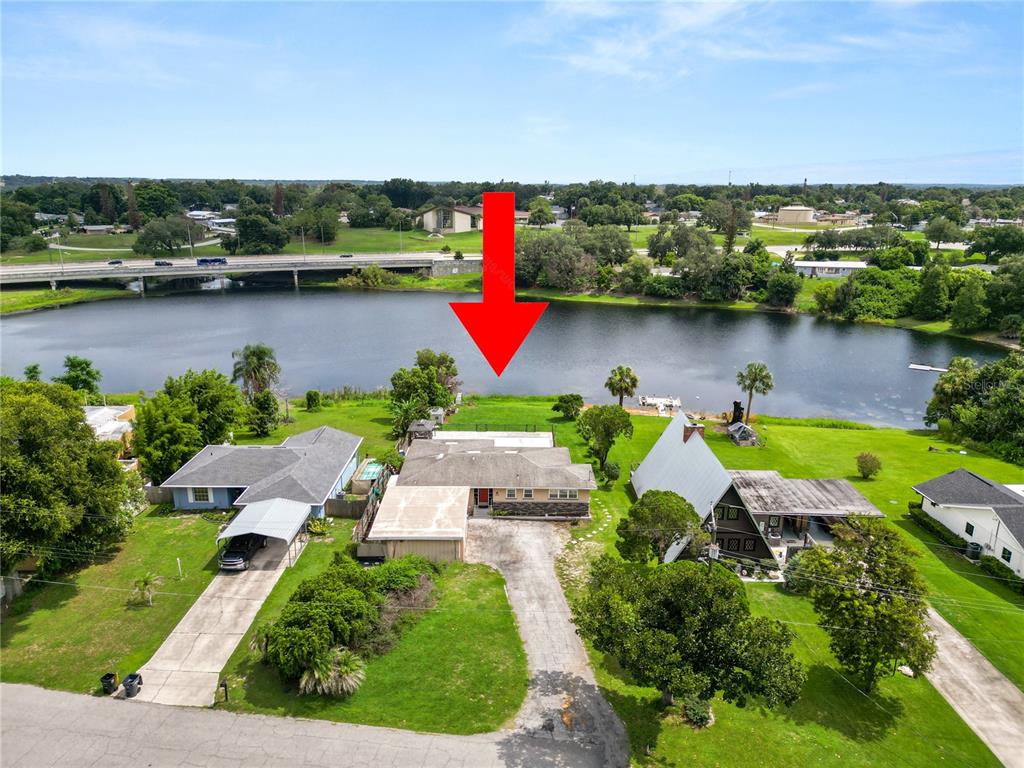 An aerial view shows a house with a pool and a large backyard facing a lake — 228 W LAKE INA DRIVE, WINTER HAVEN, FL