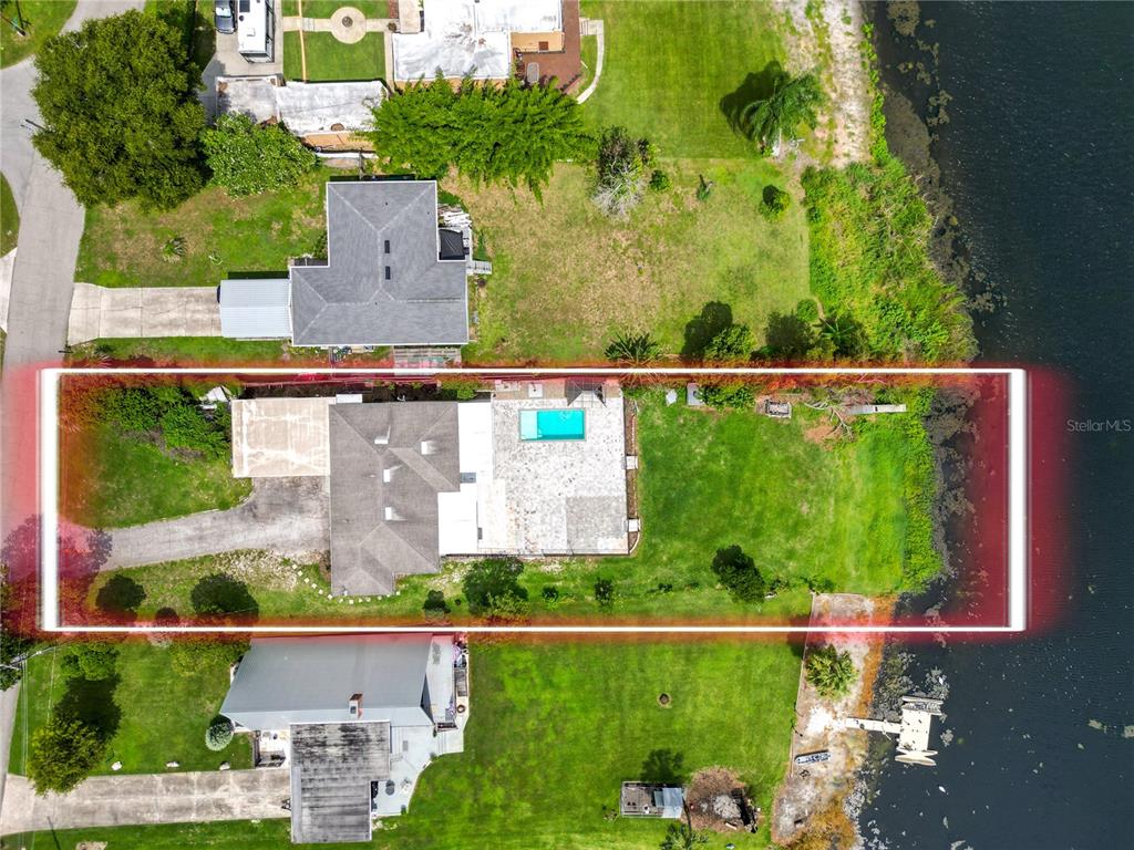 An aerial view shows a house with a pool and a large backyard bordering water — 228 W LAKE INA DRIVE, WINTER HAVEN, FL