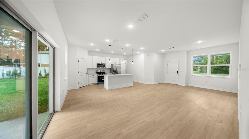 A bright, open-concept kitchen and living area features white cabinetry, a center island, and light-colored flooring — 9481 N STAFFORD DRIVE, CITRUS SPRINGS, FL