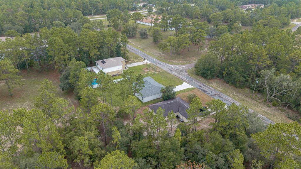 An aerial view shows three houses surrounded by dense woods near a paved road — 9481 N STAFFORD DRIVE, CITRUS SPRINGS, FL