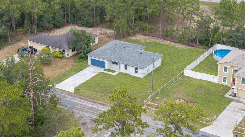 An aerial view shows three suburban houses with driveways, lawns, and a small swimming pool — 9481 N STAFFORD DRIVE, CITRUS SPRINGS, FL