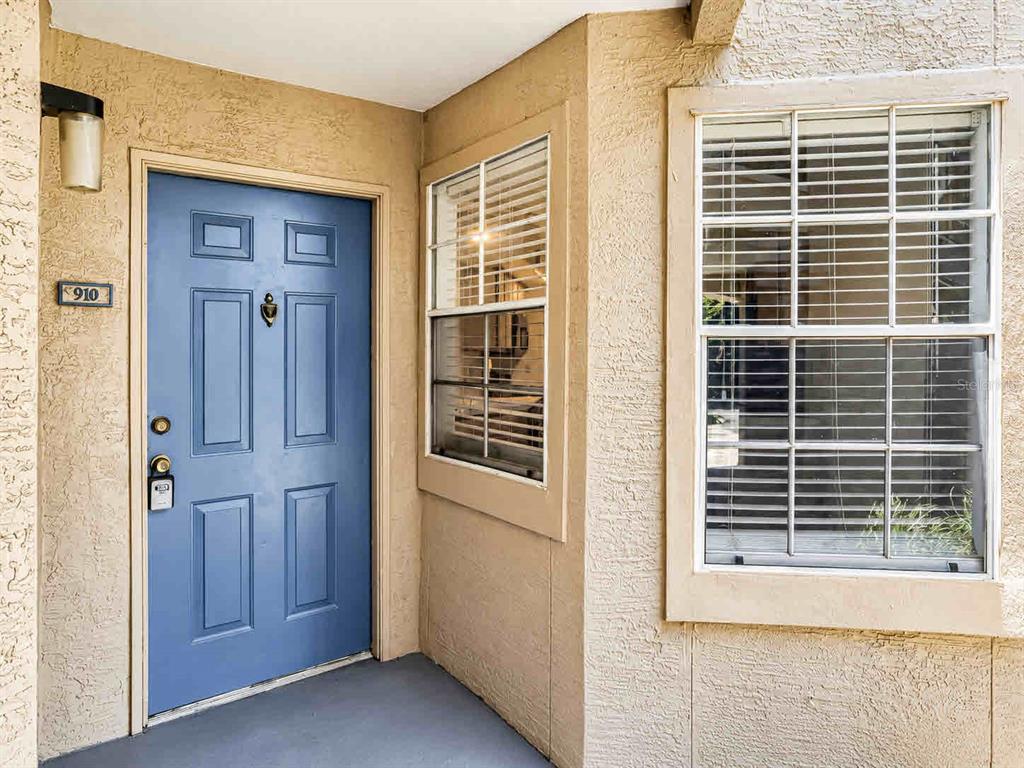An entryway with a white front door, tiled floor, and adjacent carpeted room — 7270 WESTPOINTE BOULEVARD UNIT 910, ORLANDO, FL