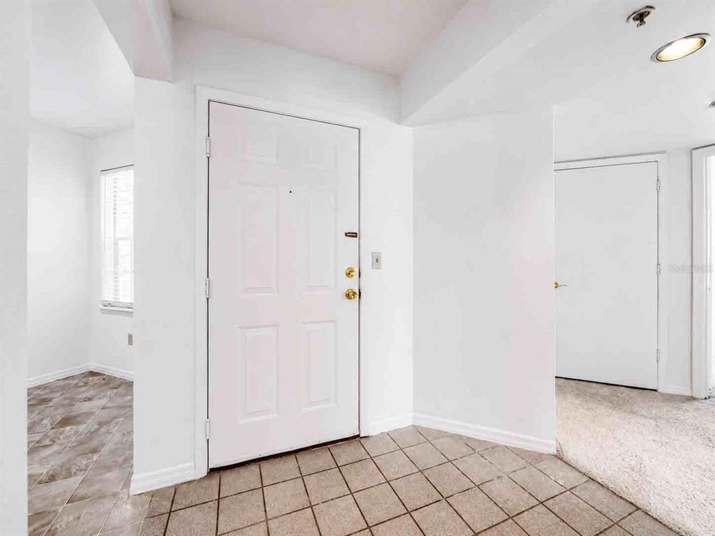 An empty living room features beige carpeting, a ceiling fan, and a sliding glass door — 7270 WESTPOINTE BOULEVARD UNIT 910, ORLANDO, FL