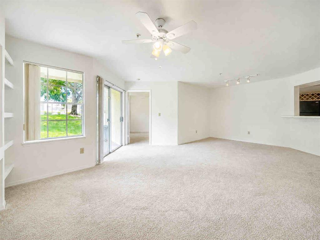 A bright living room features a beige sofa, armchair, coffee table, and a wall-mounted television — 7270 WESTPOINTE BOULEVARD UNIT 910, ORLANDO, FL