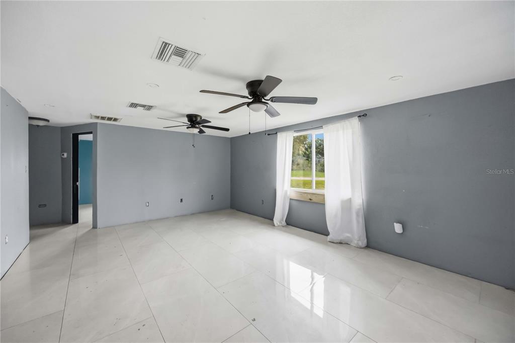 A room with gray walls, white tile flooring, two ceiling fans, and a single window — 4275 SOUTHLAND AVENUE, PORT CHARLOTTE, FL
