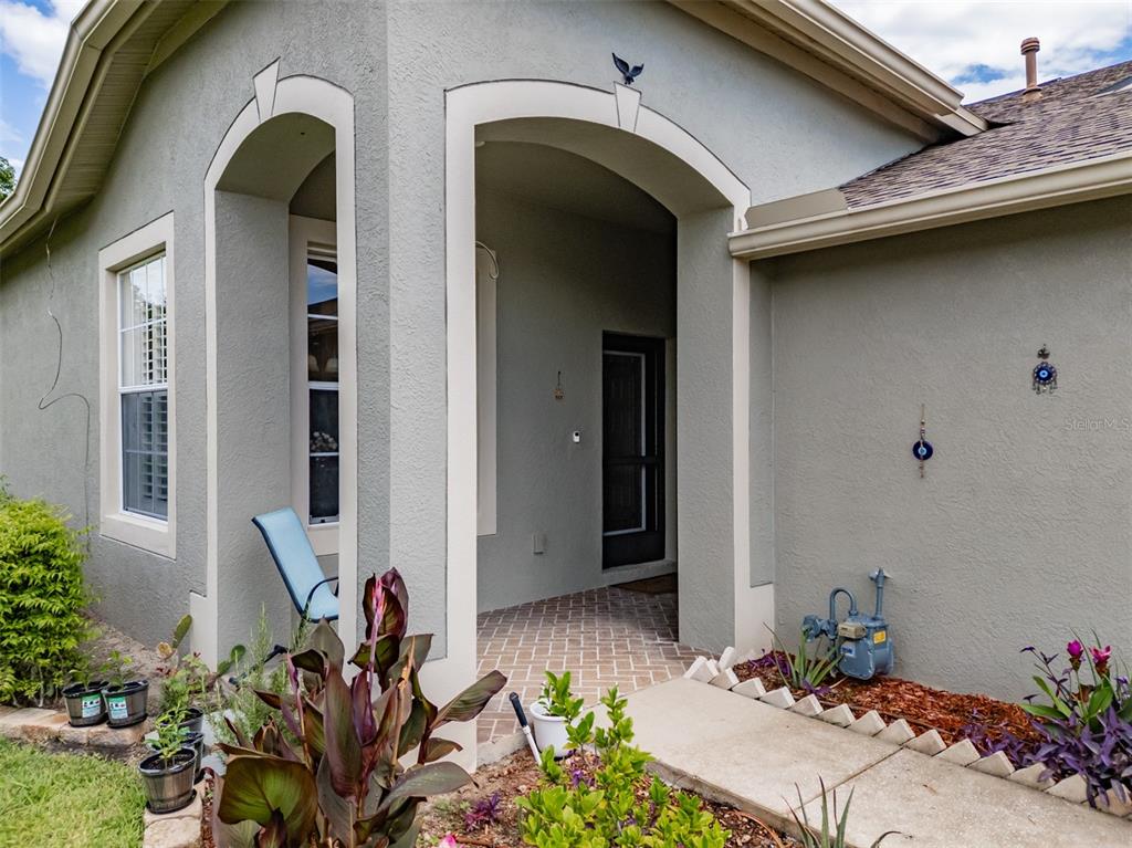 The exterior of a house features a covered entryway, a brick porch, and a gas meter — 1237 AMBRIDGE DRIVE, WESLEY CHAPEL, FL