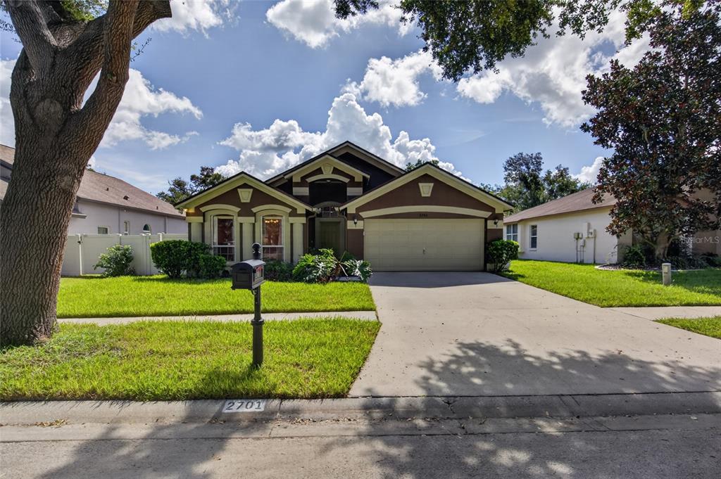 A single-story house with a two-car garage, brown stucco exterior, and a front lawn — 2701 BROOKVILLE DRIVE, VALRICO, FL
