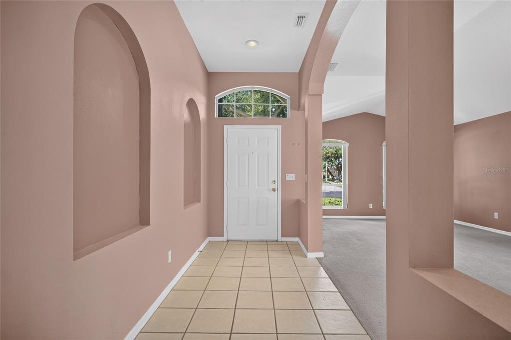 An entryway with tiled flooring, arched wall niches, and a white front door with transom — 2701 BROOKVILLE DRIVE, VALRICO, FL