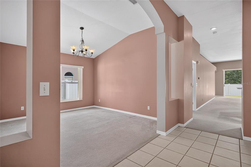 A carpeted dining room features a vaulted ceiling, a chandelier, and a large window — 2701 BROOKVILLE DRIVE, VALRICO, FL