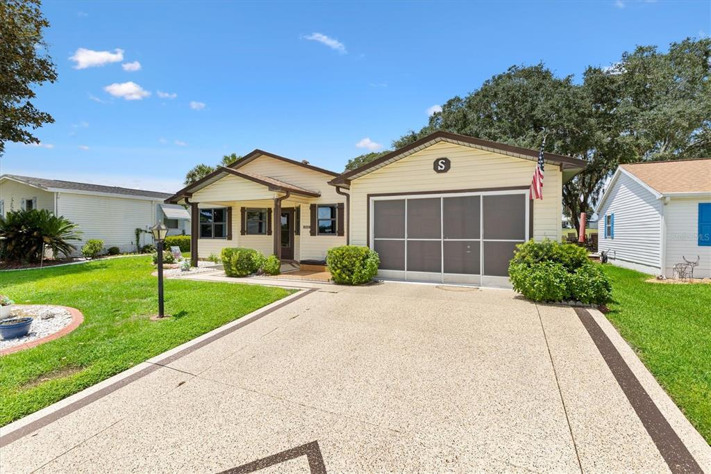 A light yellow house with a screened garage and a concrete driveway under a blue sky — 1532 E SCHWARTZ BOULEVARD, LADY LAKE, FL
