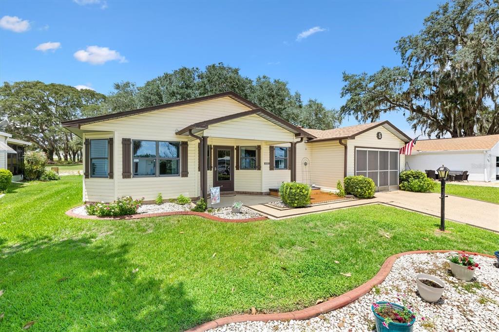 A single-story house with light yellow siding, a front porch, and a landscaped yard — 1532 E SCHWARTZ BOULEVARD, LADY LAKE, FL