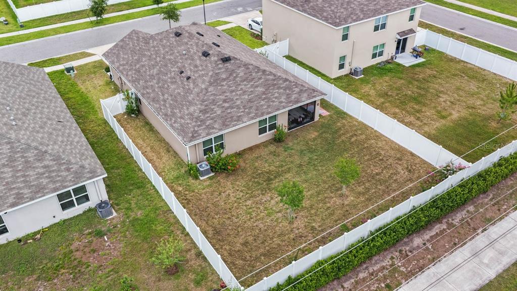 An aerial view shows a tan, single-story suburban house with a brown shingled roof — 1911 BLUE STREAM STREET, RUSKIN, FL