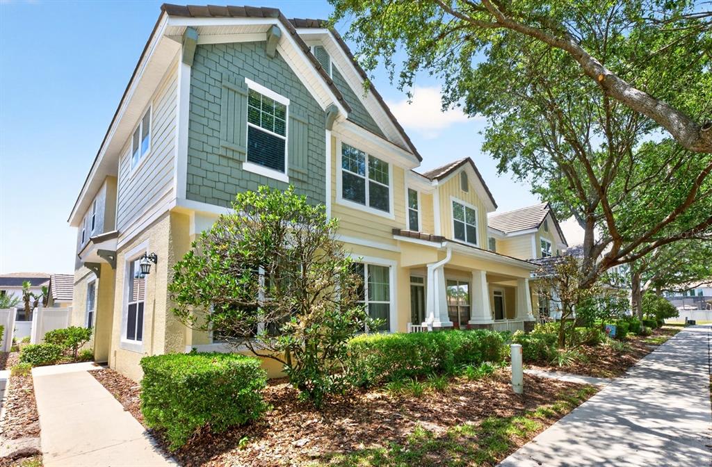 A two-story townhouse with yellow siding, green shingle accents, and a front porch — 7330 BRIGHTLAND STREET, WINDERMERE, FL