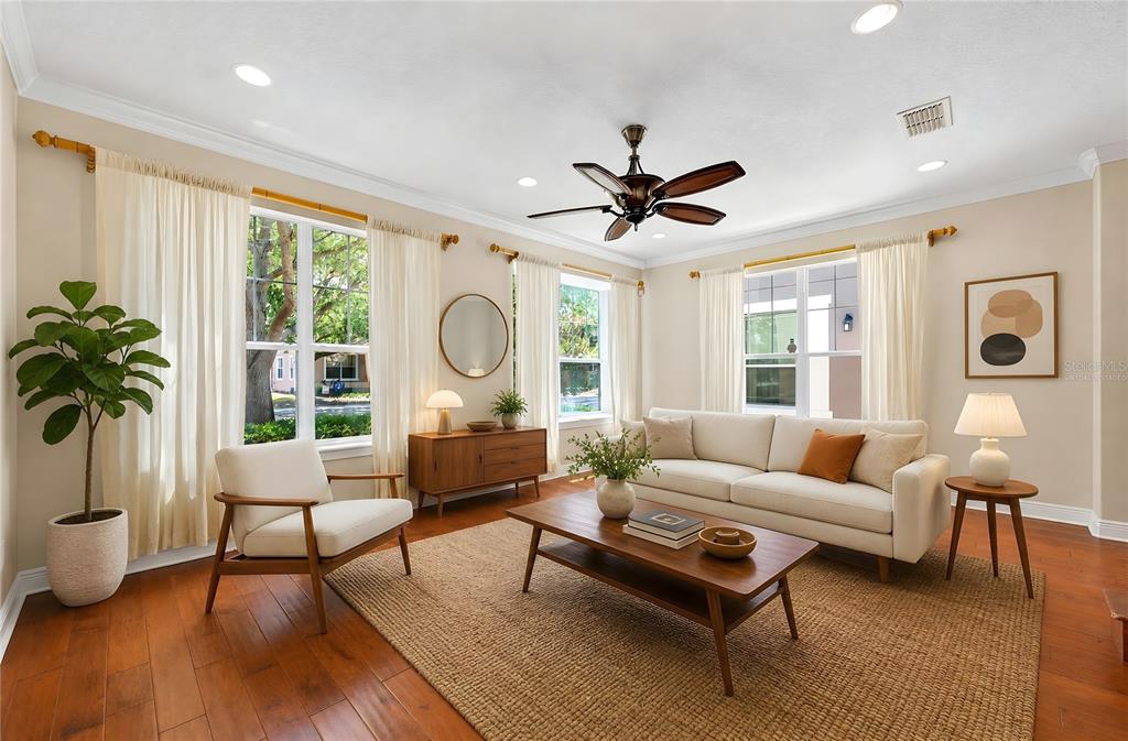 A living room features a white sofa, mid-century modern armchair, wooden coffee table, and hardwood floors — 7330 BRIGHTLAND STREET, WINDERMERE, FL