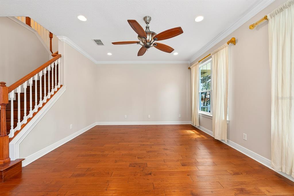 An empty room with hardwood floors, a ceiling fan, and a staircase with wooden railings — 7330 BRIGHTLAND STREET, WINDERMERE, FL