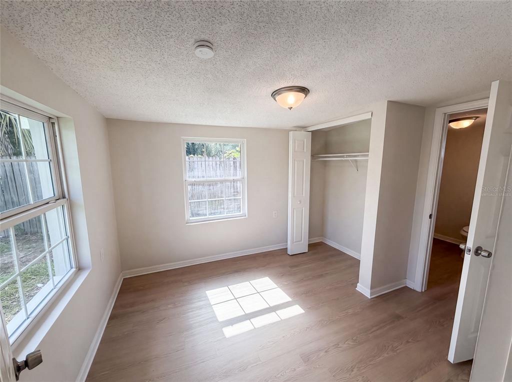 An empty bedroom features light wood-look flooring, a window, a closet, and a doorway — 3665 MIAMI AVENUE, MELBOURNE, FL