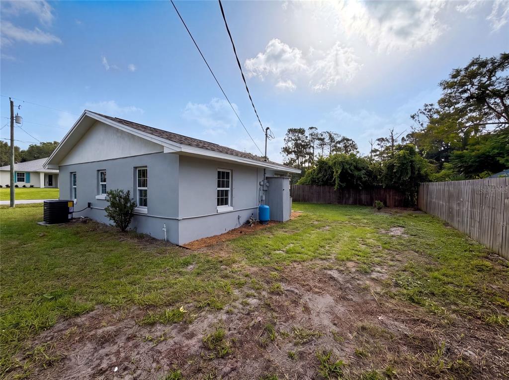 The exterior side and backyard of a gray house with a wooden fence — 3665 MIAMI AVENUE, MELBOURNE, FL