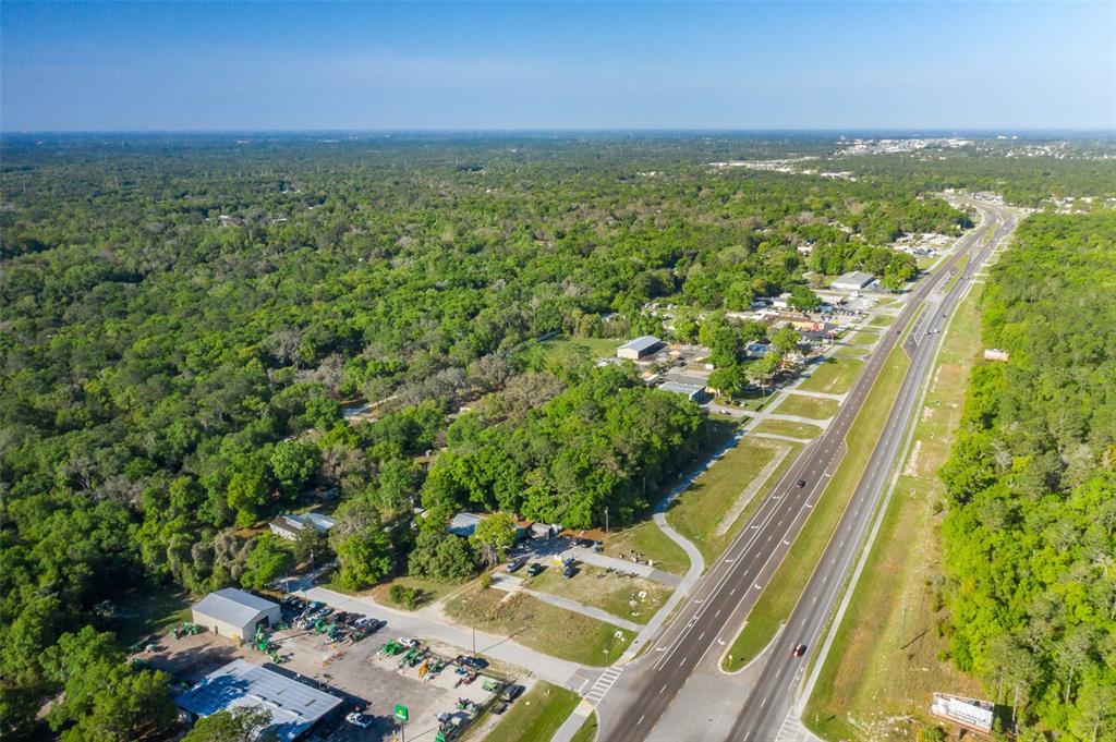 An aerial view shows a commercial property with a parking lot beside a multi-lane highway — 17022 CORTEZ BOULEVARD, BROOKSVILLE, FL