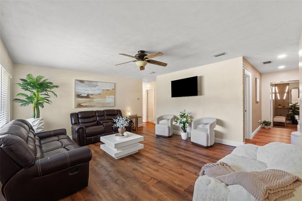 A living room features dark leather sofas, white accent chairs, a central coffee table, and wood-look flooring — 1721 S JEFFERSON AVENUE, CLEARWATER, FL