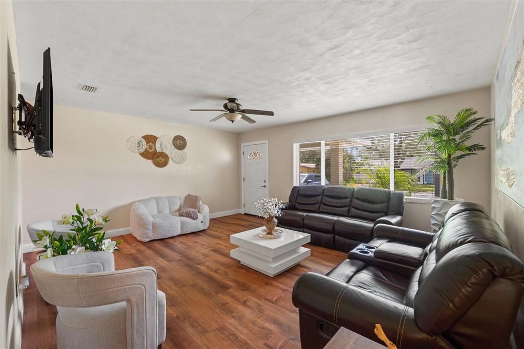 A living room features wood-look flooring, a ceiling fan, a white coffee table, and leather seating — 1721 S JEFFERSON AVENUE, CLEARWATER, FL